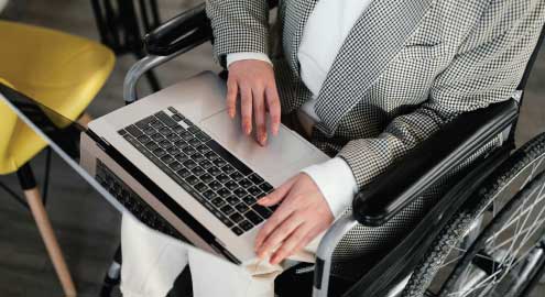 Person in a wheelchair with a laptop in their lap.